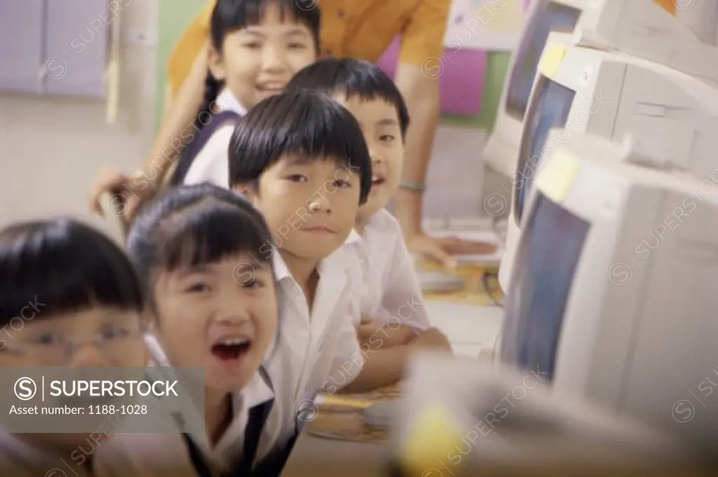 Portrait of children sitting in front of computers