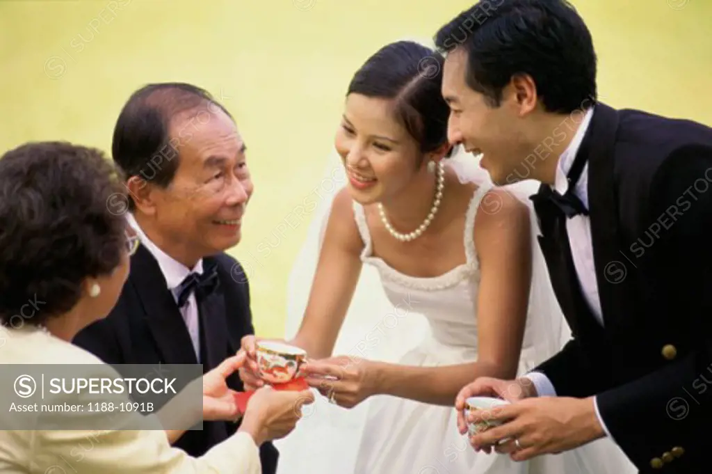 Newlywed couple offering tea to their parents