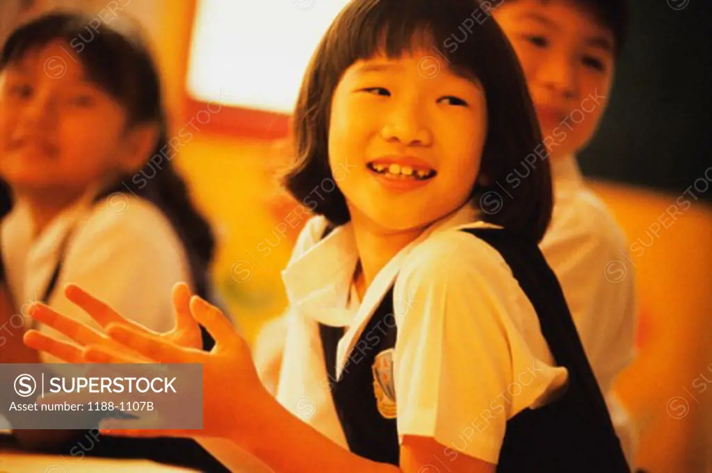 Close-up of a schoolgirl clapping and smiling in a classroom