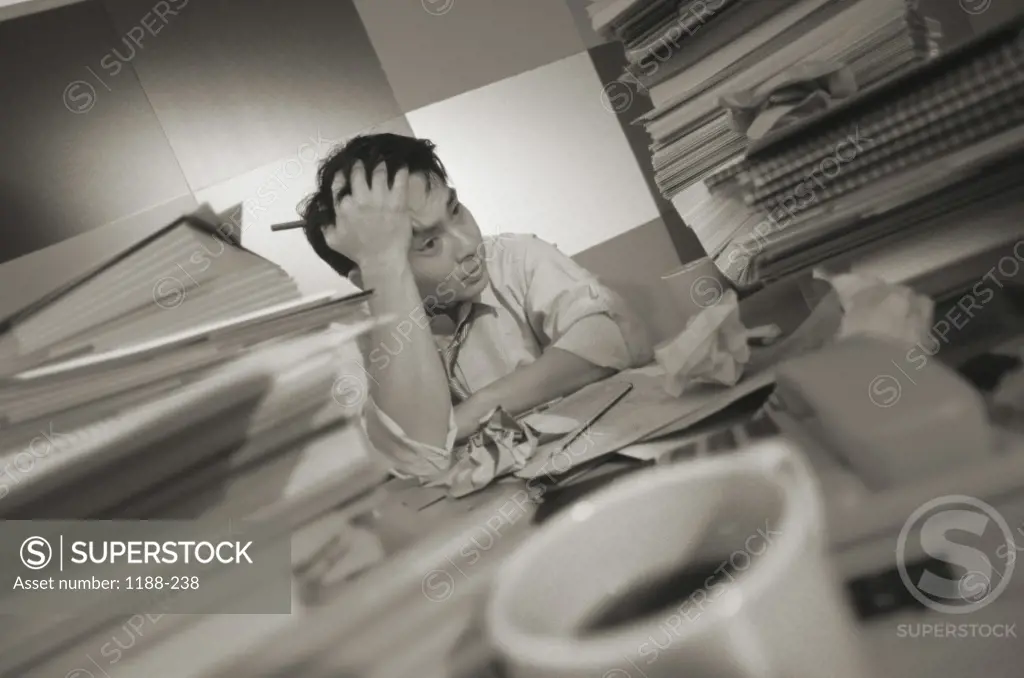 Businessman sitting at a desk with a pile of paperwork