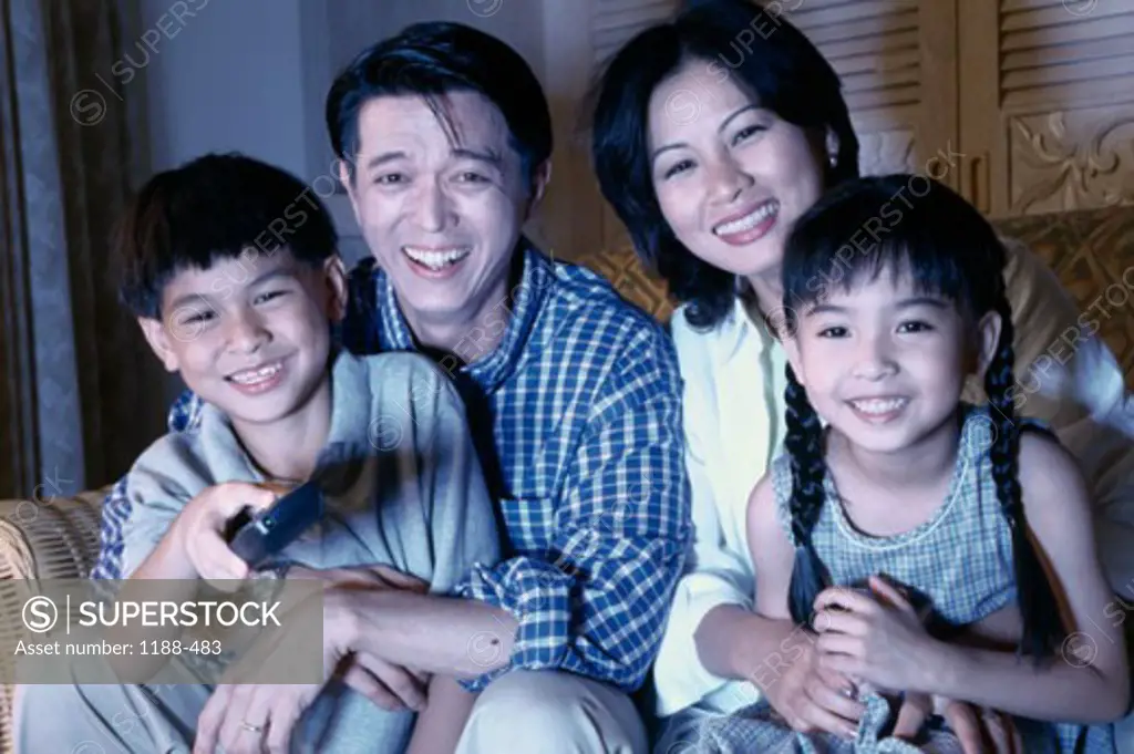 Close-up of parents sitting with their two children watching television