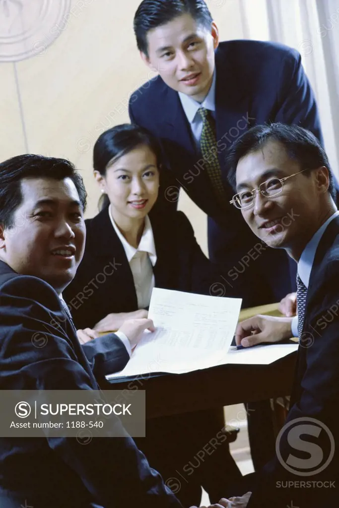 Portrait of three businessmen and a businesswoman smiling in an office