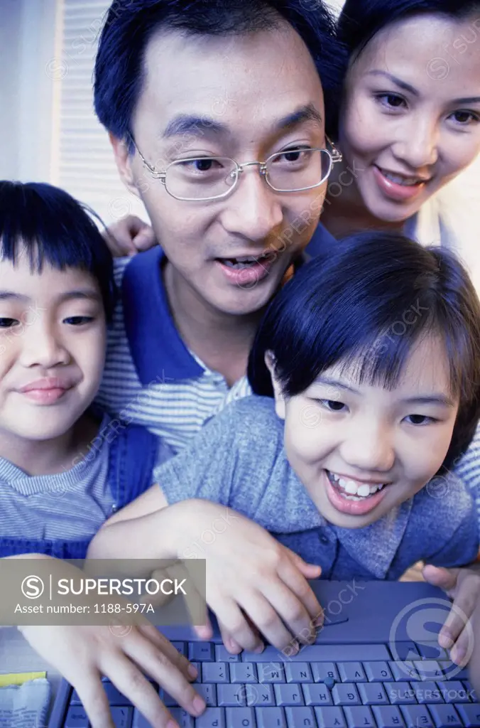 Close-up of parents and their son and daughter using a laptop