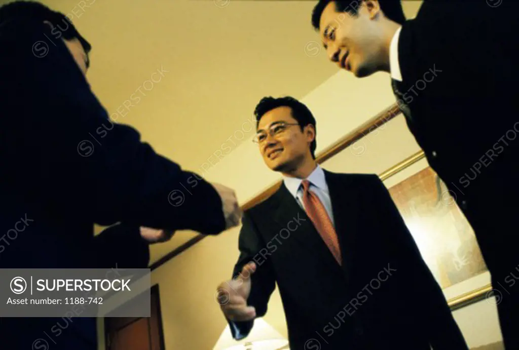 Low angle view of three businessmen shaking hands in an office
