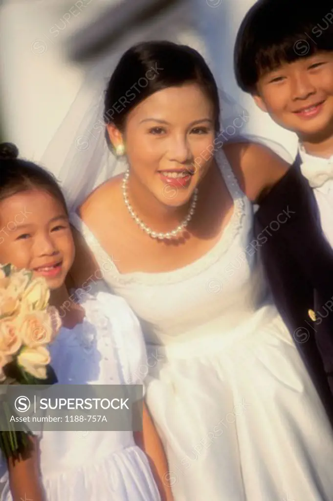 Portrait of a bride standing with a flower girl and a ring bearer