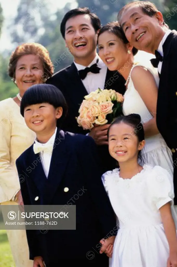 Newlywed couple standing with their family and smiling