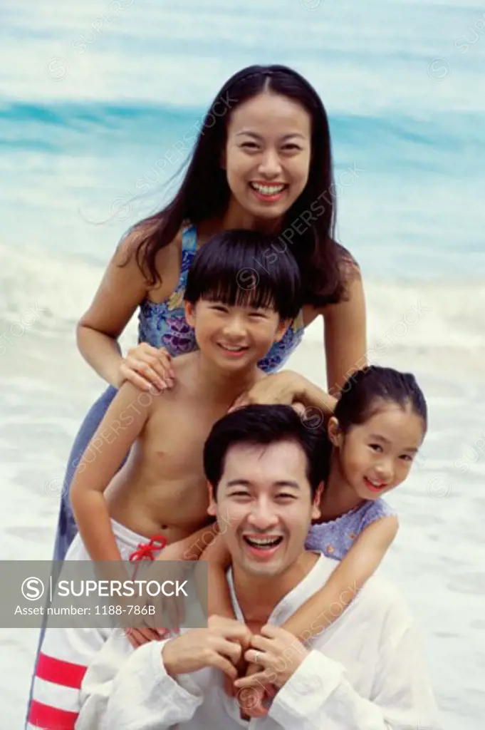 Mid adult couple with their son and daughter smiling on the beach