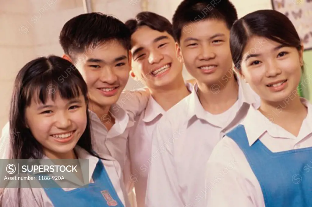 Five teenagers smiling in a classroom