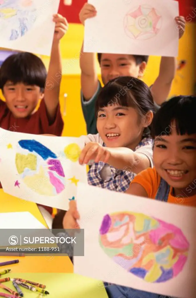 Two girls and two boys showing their drawings and smiling
