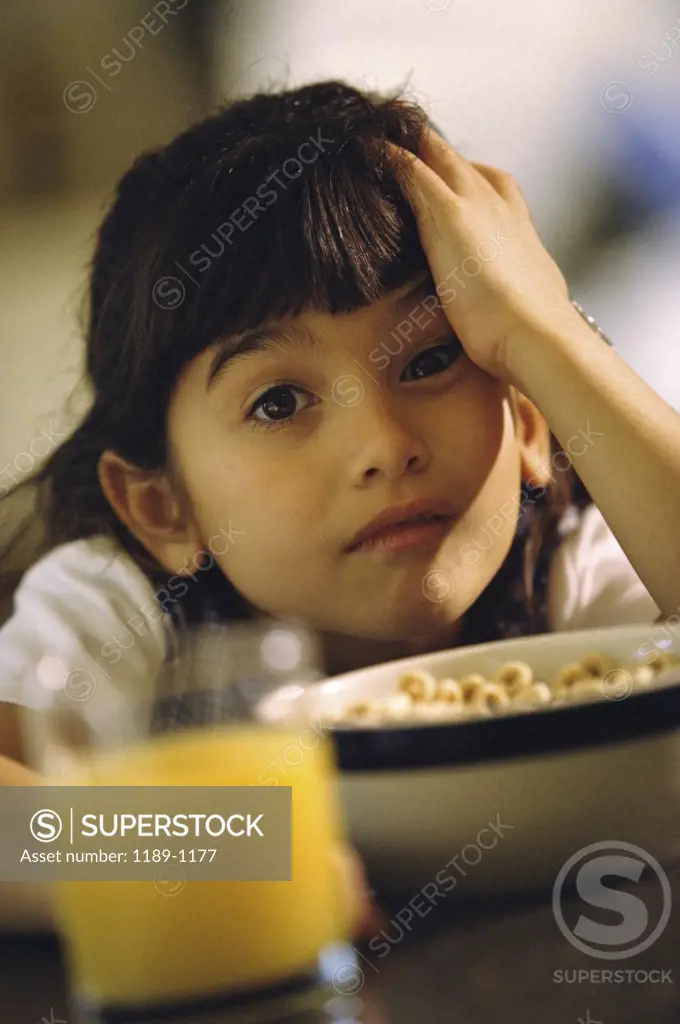 Portrait of a girl sitting at a table with her hand on her head