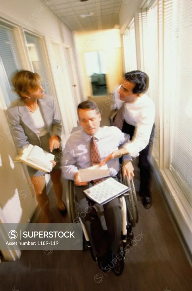 High angle view of two businessmen with a businesswoman in a corridor