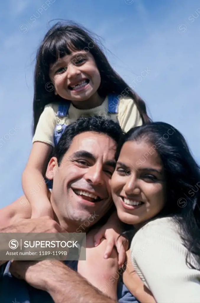 Portrait of a mid adult man carrying his daughter on his shoulders with a mid adult woman smiling