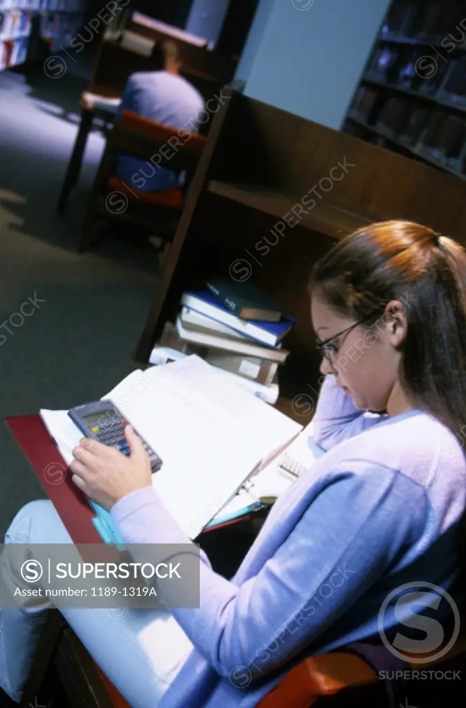 Side profile of a teenage girl reading a book in a library