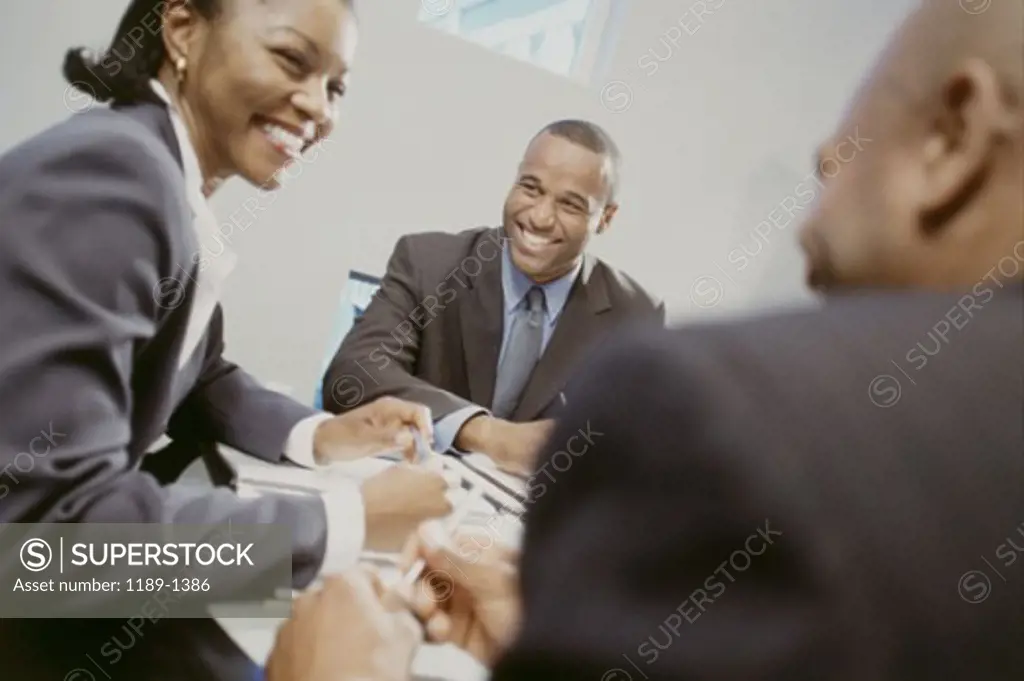 Two businessmen and a businesswoman sitting in a meeting