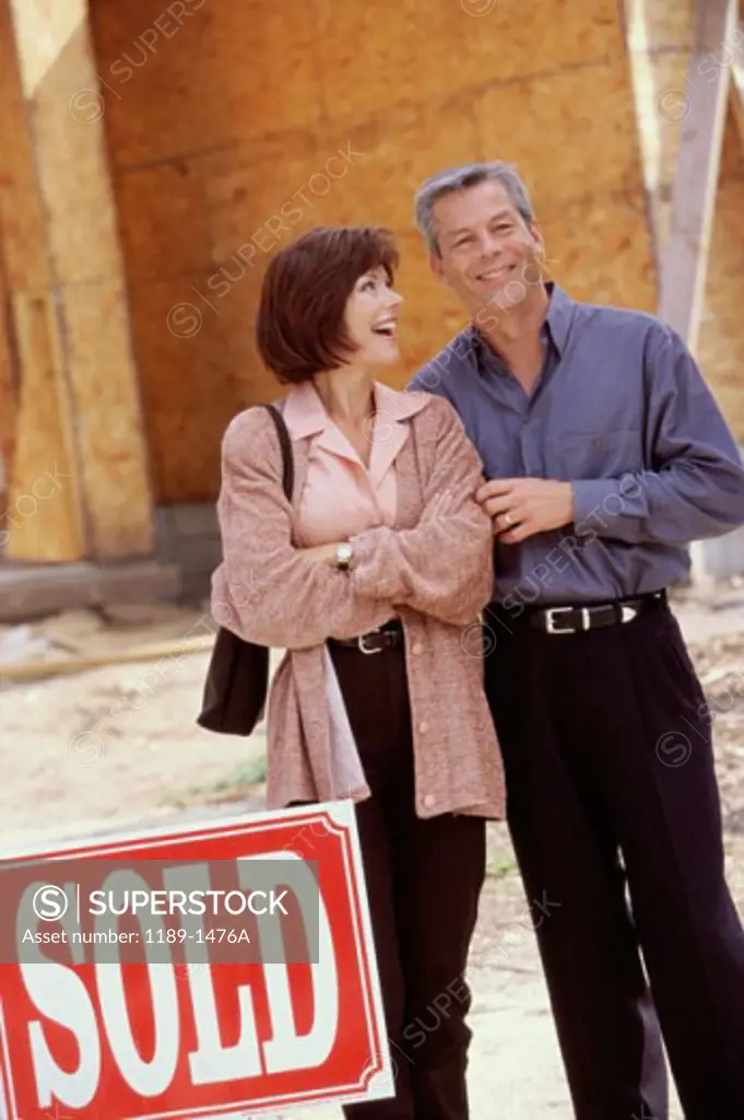 Mature couple standing in front of a new house