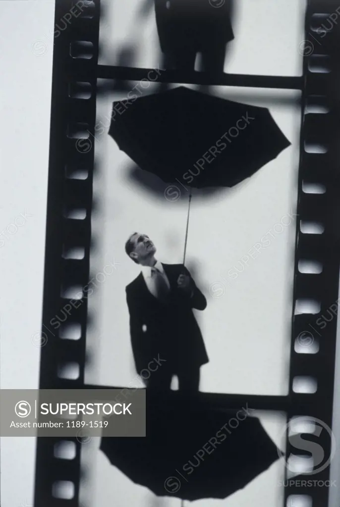 Close-up of a film strip of a businessman holding an umbrella up side down