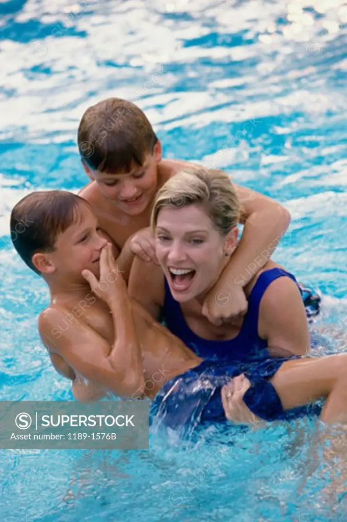 High angle view of a mid adult woman with her two sons in a swimming pool