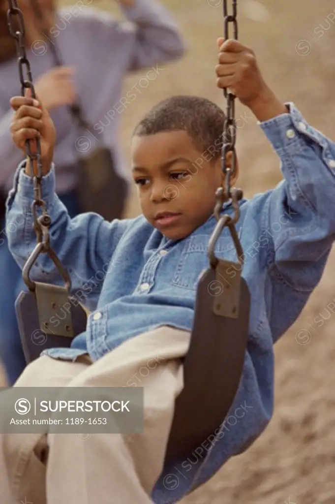 Close-up of a boy swinging on a swing