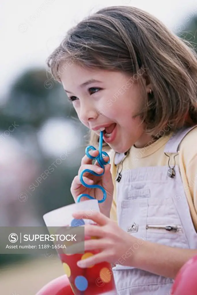 Close-up of a girl drinking juice with a drinking straw