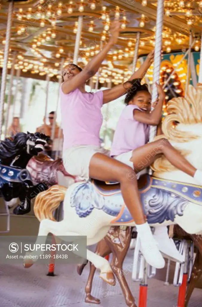 Mid adult woman with her daughter riding a carousel horse