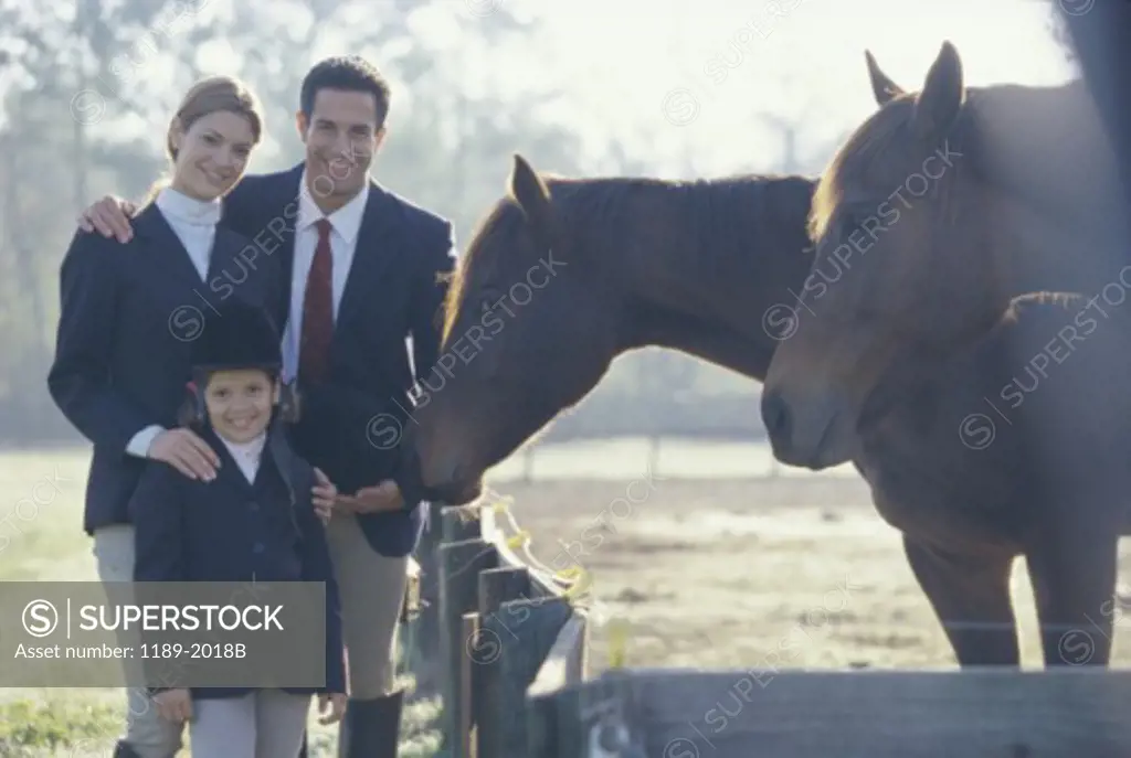 Portrait of a family standing beside two horses