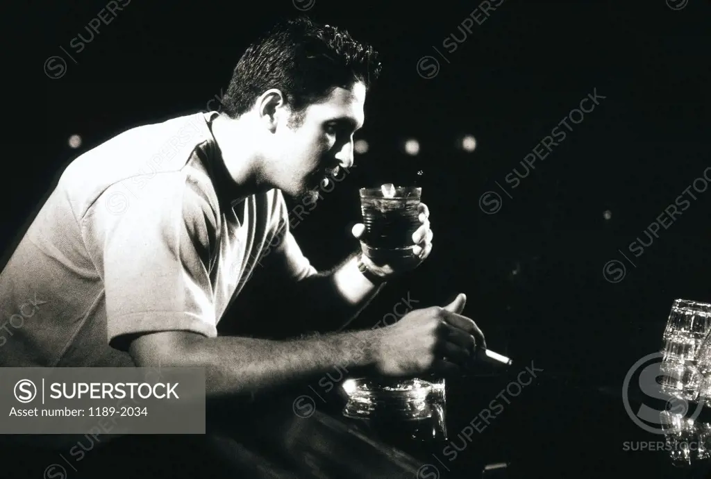 Side profile of a young man drinking and smoking