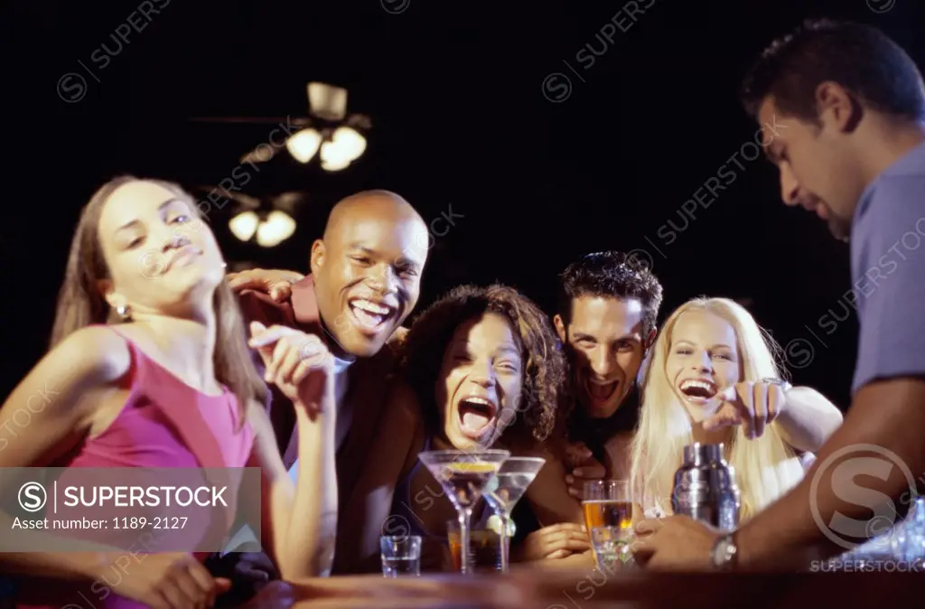 Portrait of five young people shouting at a bar