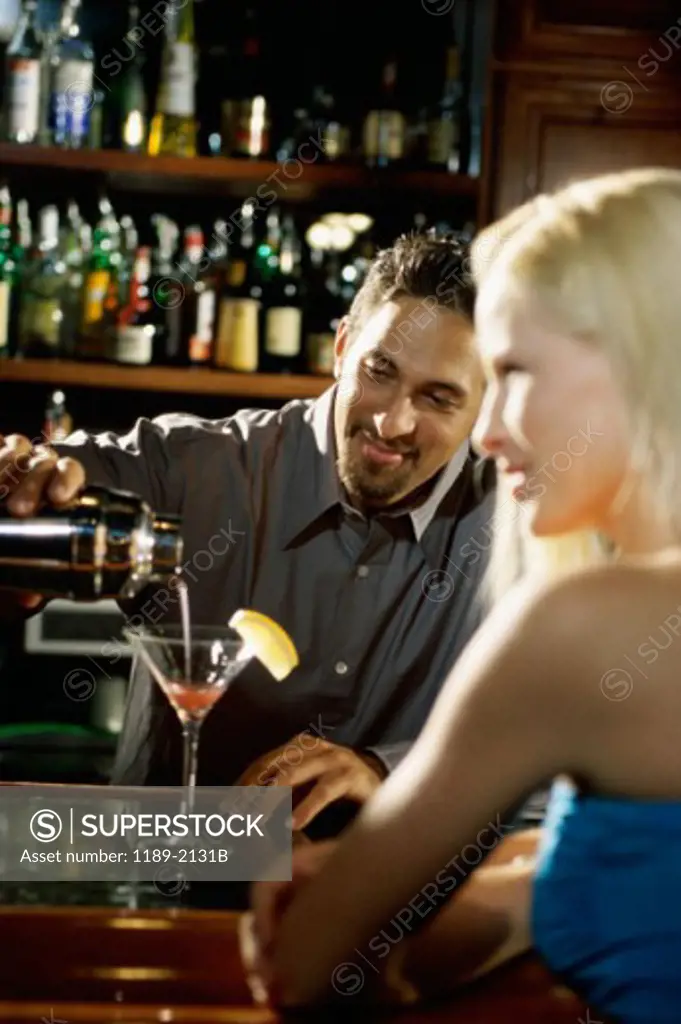 Bartender making a drink for a young woman in a bar