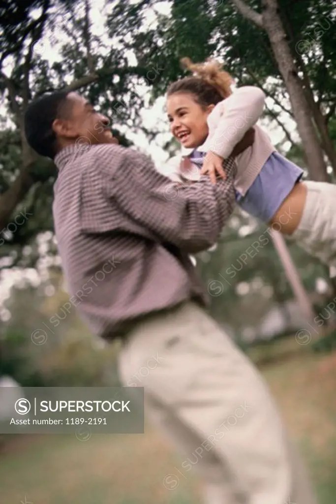 Side profile of a father swinging his daughter