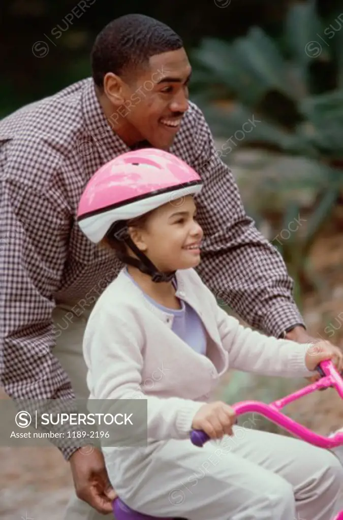 Side profile of a father helping his daughter ride a bicyle