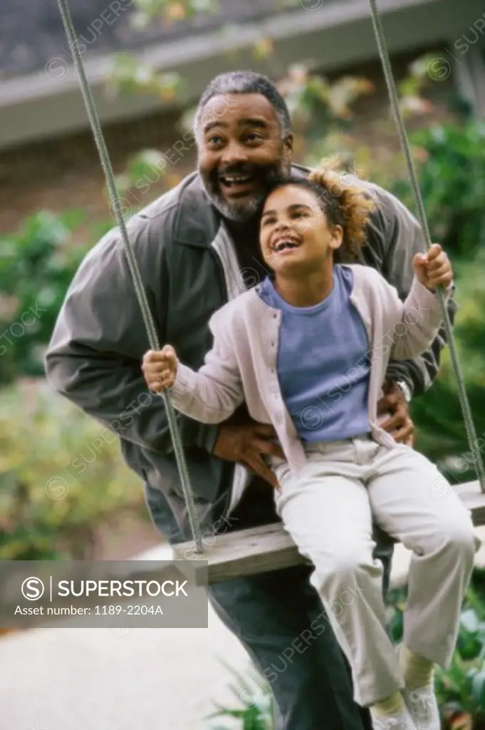 Grandfather pushing his granddaughter on a swing