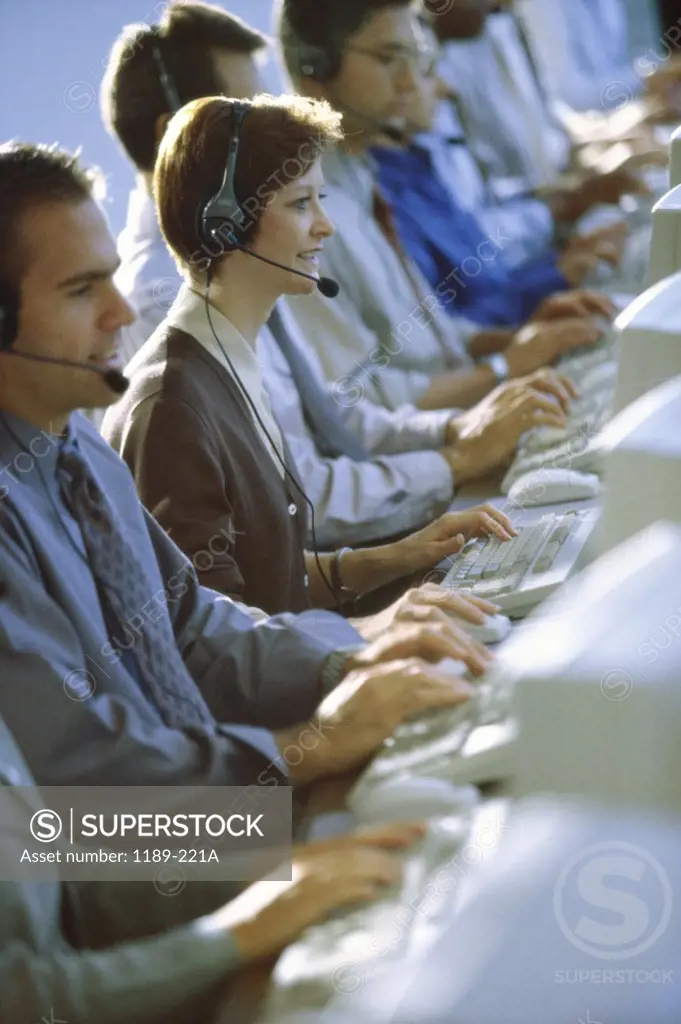 Side profile of business executives wearing headsets working on computers
