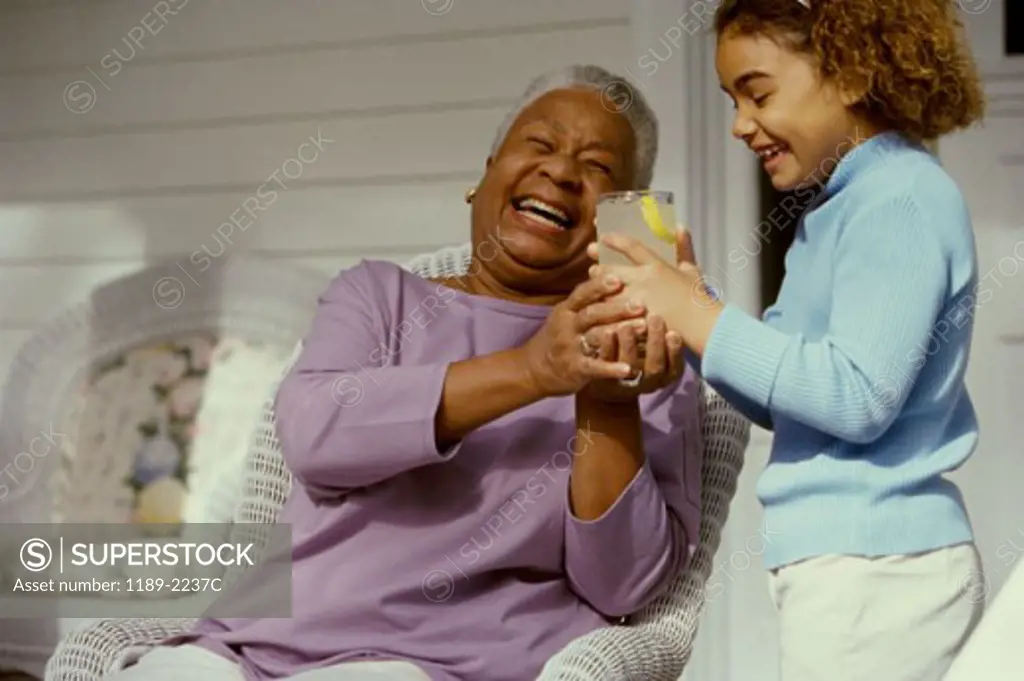 Senior woman and her granddaughter holding a glass of lemonade