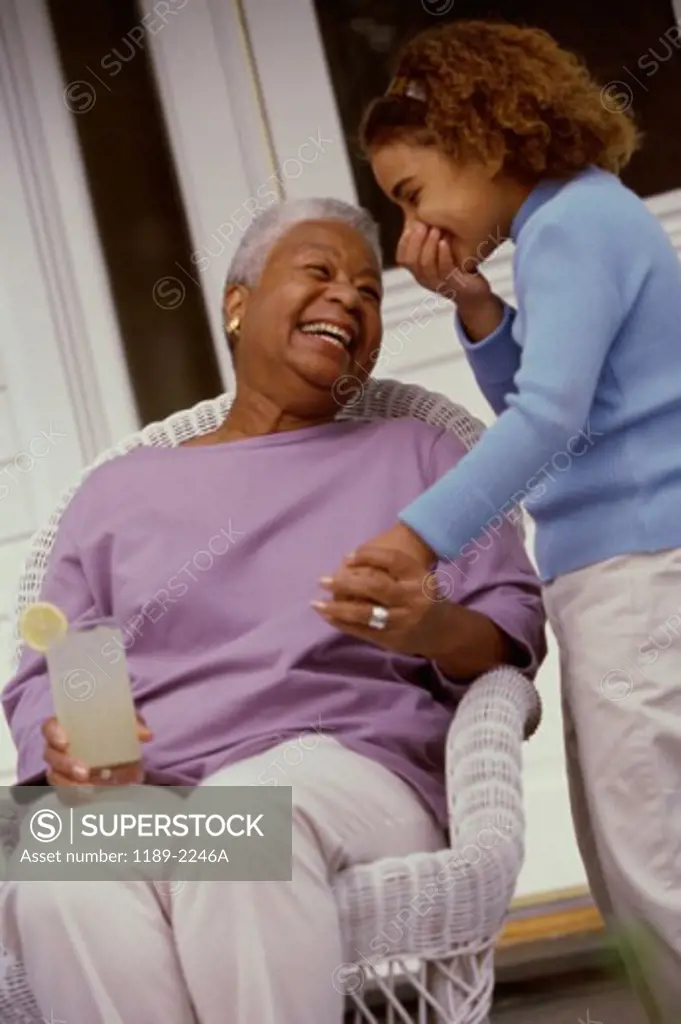 Grandmother holding a glass of lemonade with her granddaughter standing beside her
