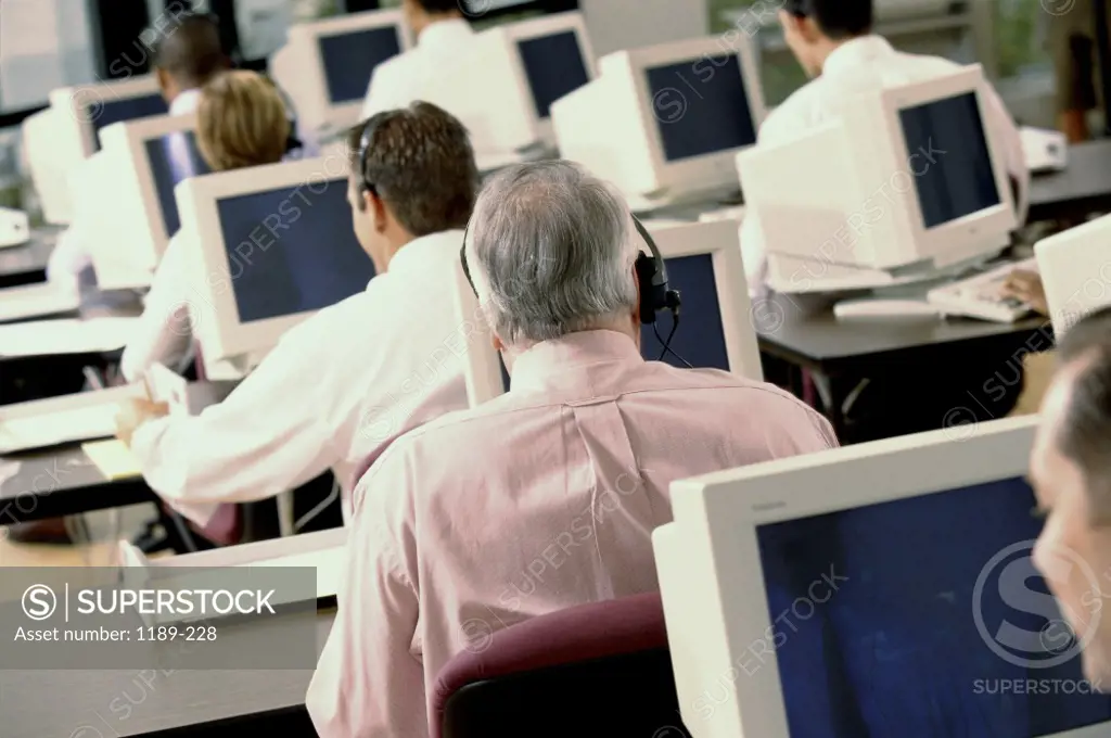 Rear view of business executives wearing headsets working on computers
