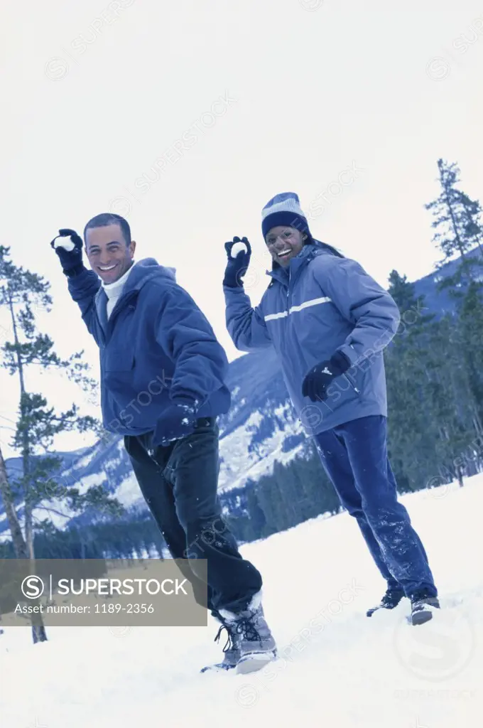 Portrait of a young couple throwing snowballs