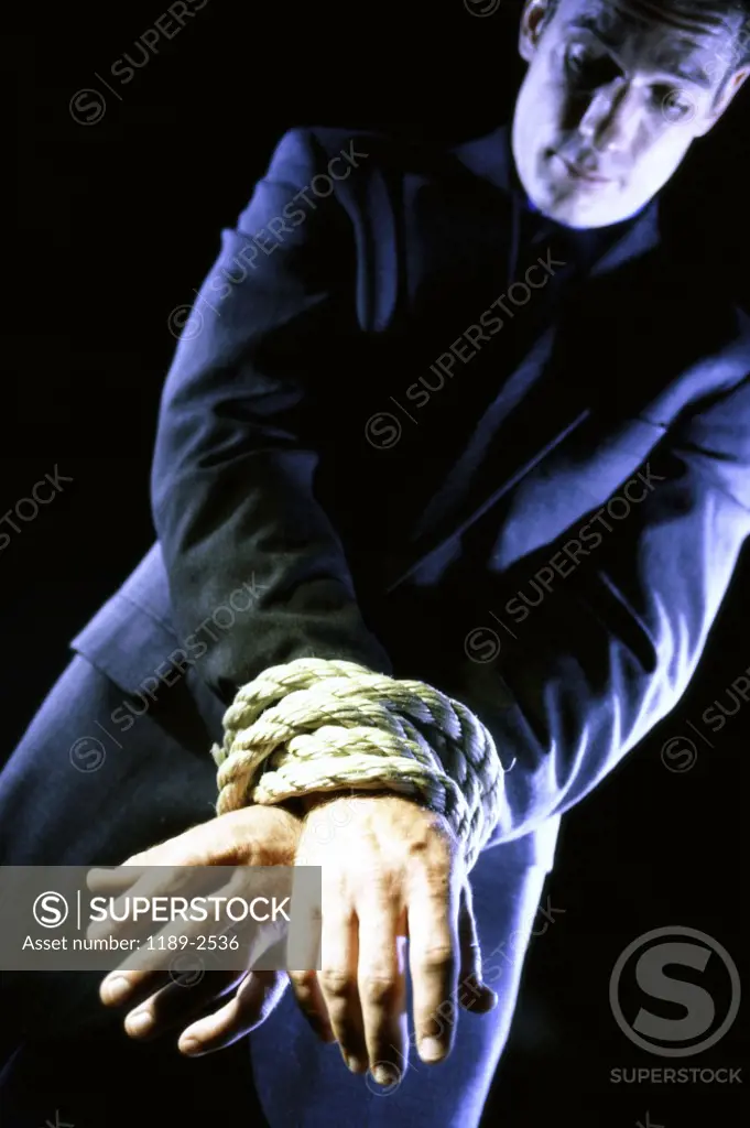 Businessman's hands tied together with a rope