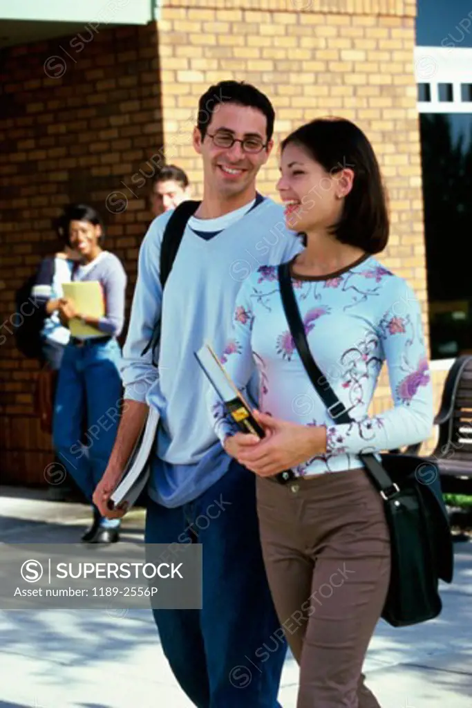 Young man and a young woman walking on a college campus