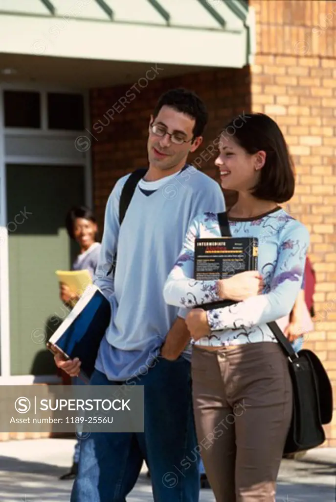 Young man and a young woman walking on a college campus