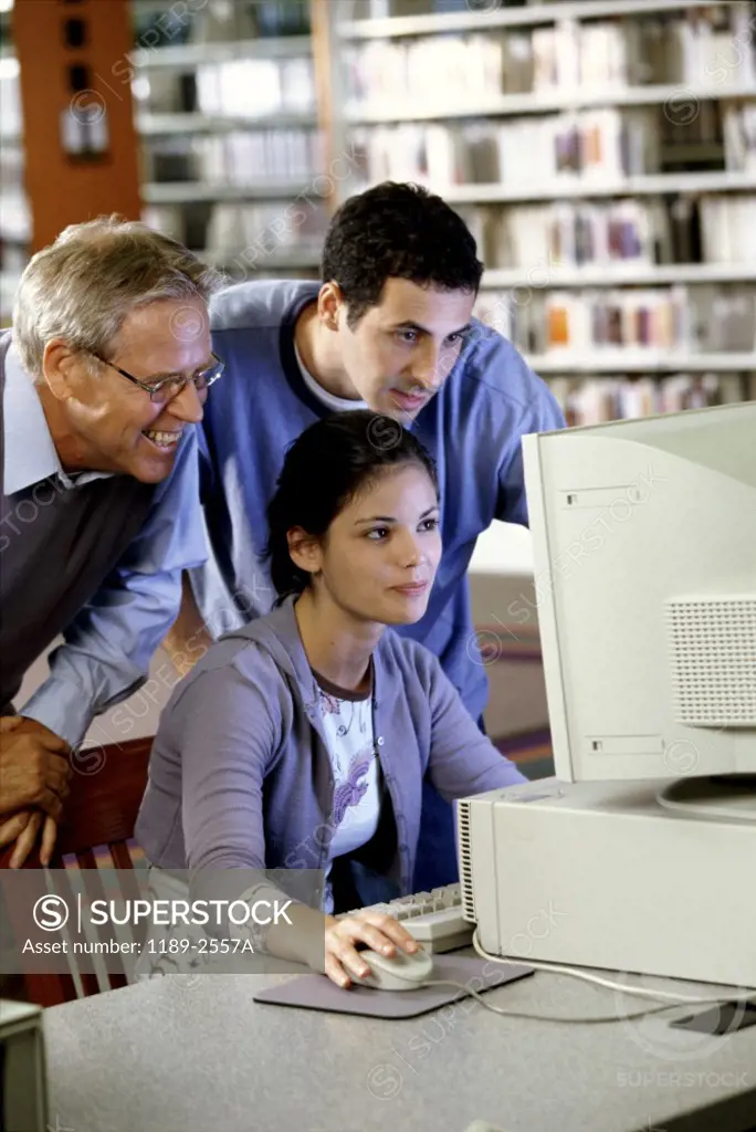 Male teacher with a teenage girl and a teenage boy in front of a computer