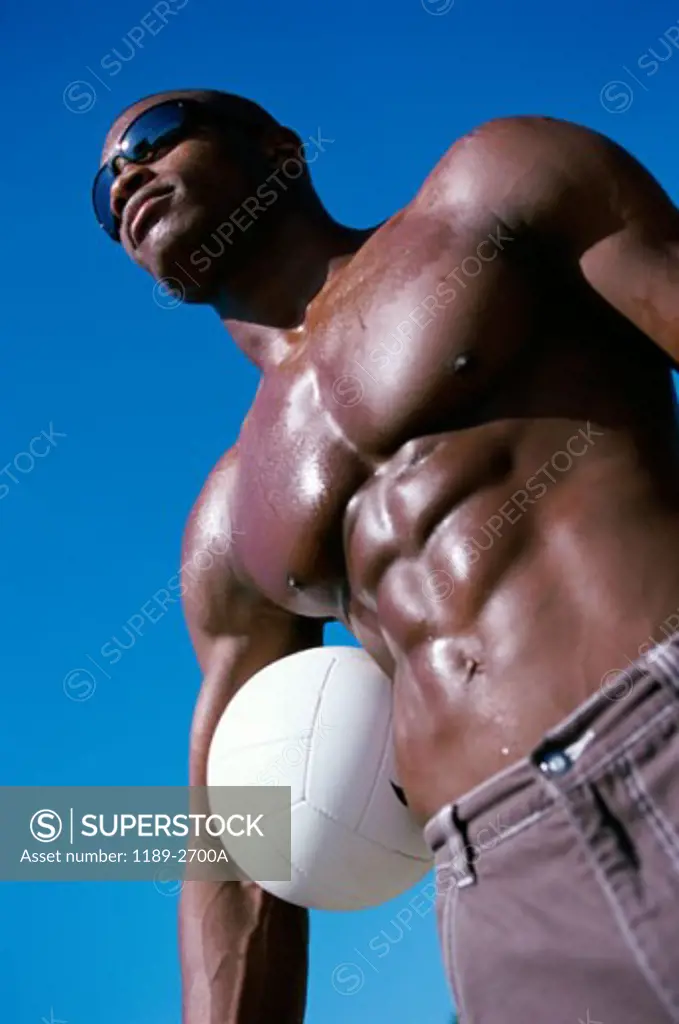 Low angle view of a young man holding a volleyball