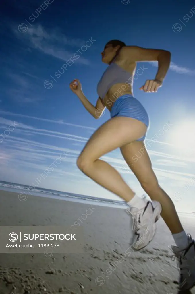 Low angle view of a young woman jogging on the beach
