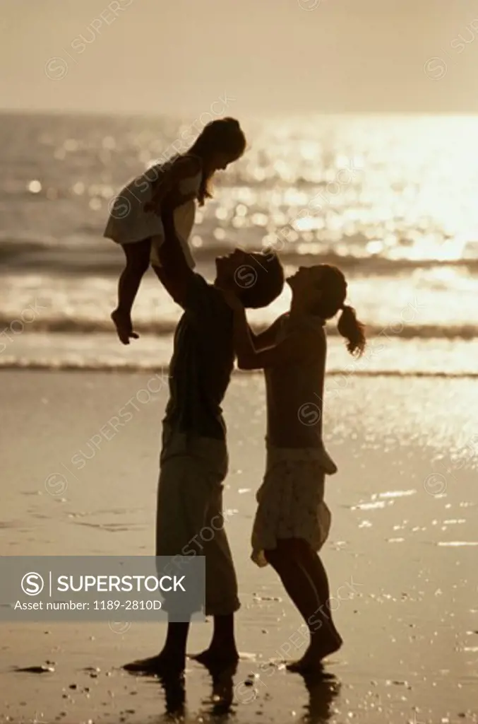 Silhouette of a young couple with their daughter on the beach