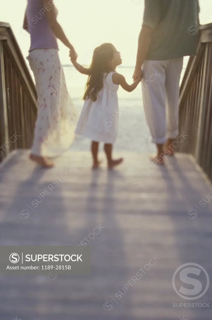 Rear view of a girl with her parents walking on a boardwalk