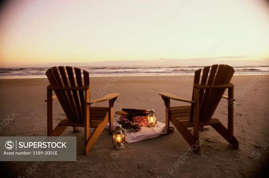 Two lanterns and two lawn chairs on the beach