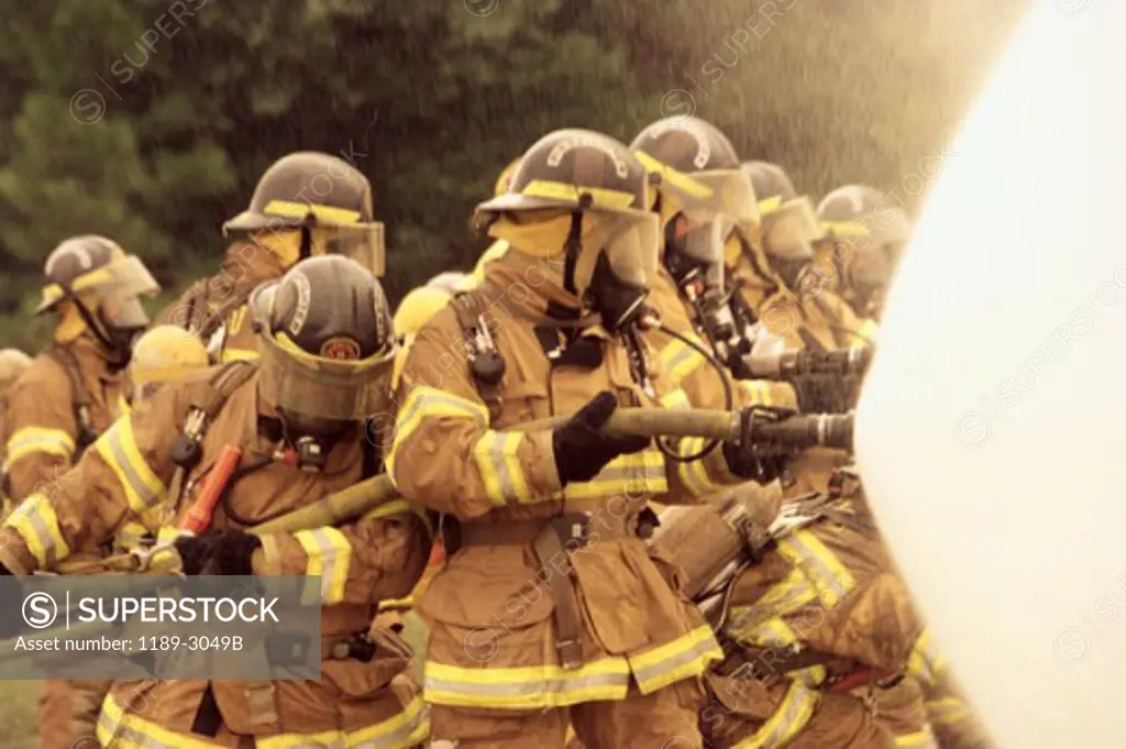 Group of firefighters spraying water with a fire hose