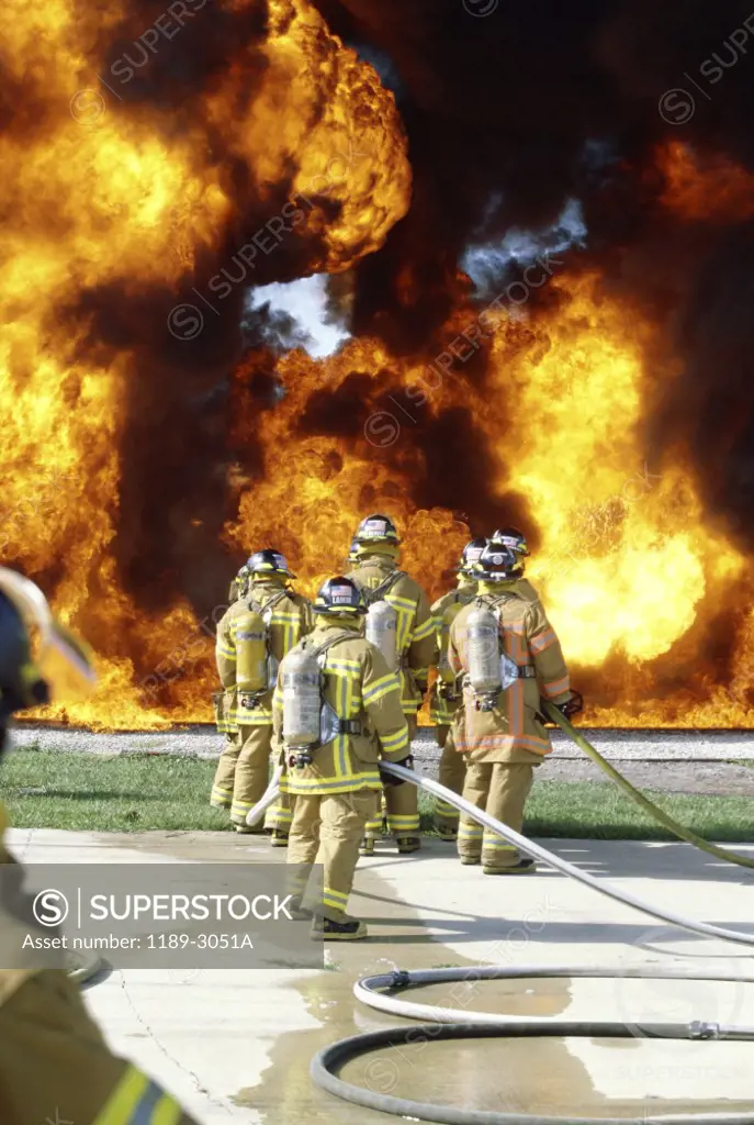 Rear view of a group of firefighters extinguishing a fire
