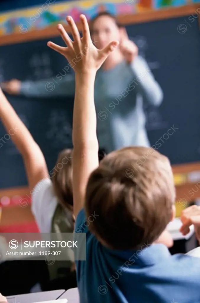 Group of children with their hands raised in a classroom