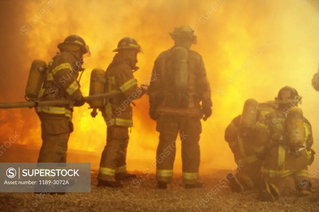 Rear view of a group of firefighters extinguishing a fire