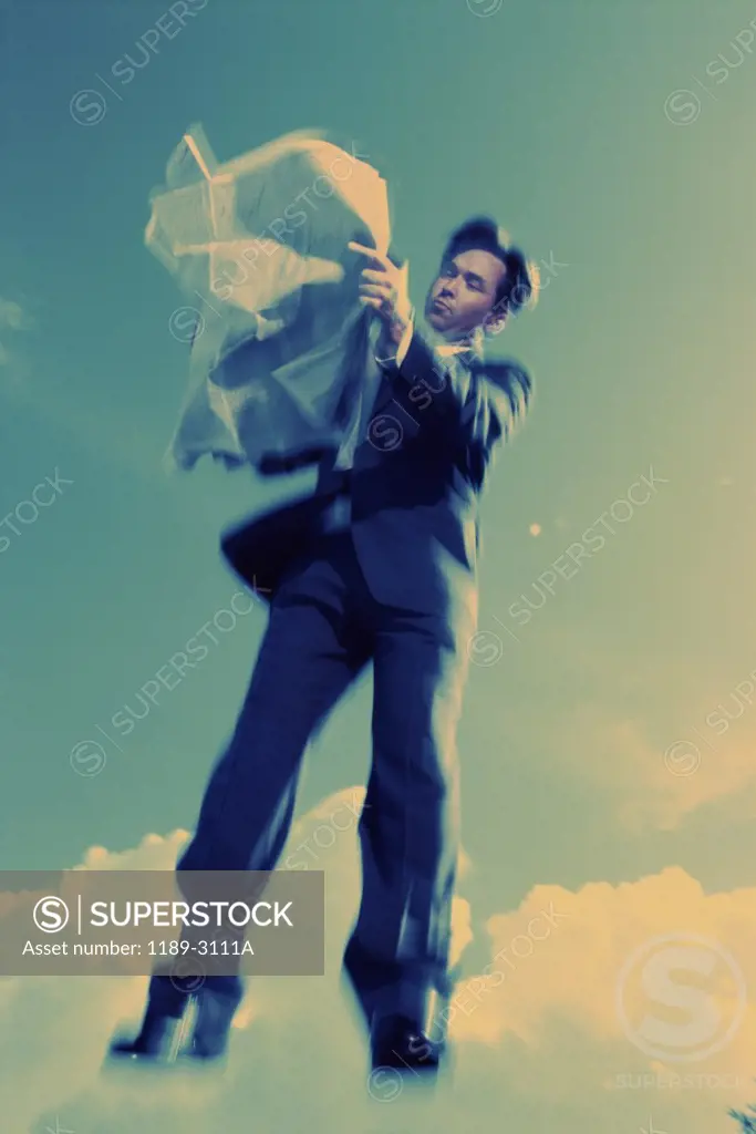 Low angle view of a businessman reading a newspaper in mid-air